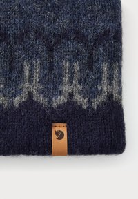 Navy blue knit wool beanie with light gray pattern resembling a city skyline and a small tan leather tag with a fox logo.