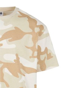 Lysbeige bomulds T-shirt med et camouflage mønster i forskellige nuancer af tan og creme, med en klassisk rund hals og korte ærmer.
