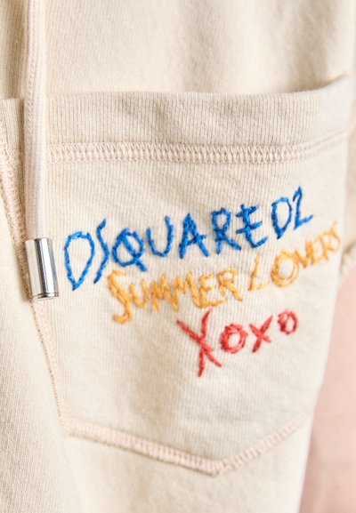 Bežna tkanina s izvezenim tekstom u plavoj, narančastoj i crvenoj boji: "DSQUARED2 LJUBITELJI LETA XOXO." Ima mali džep i metalni detalj.