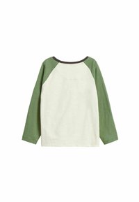 Pitkähihaisen T-paidan vihreä raglan-malli. Kerma-valkoinen vartalo vihreillä hihoilla, pyöreä pääntie ja pehmeä, teksturoitu kangas. Ei näkyviä kuvioita.