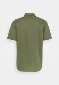 Camicetta a maniche corte di colore verde oliva, realizzata in tessuto leggero, con colletto classico, vestibilità comoda e fondo curvo senza branding visibile.