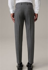 Grijze op maat gemaakte broek van textuurstof, met een vlakke voorkant, twee achterzakken en een slim fit. Draagt met zwarte schoenen.