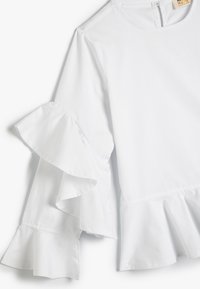 Weiße Bluse mit langen, Rüschensäumen, rundem Ausschnitt und einem Peplum-Saum. Aus leichtem, glattem Baumwollstoff gefertigt.