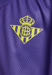 Lila sporttröja i texturerat tyg med en gul logotyp som har en krona och geometrisk design.