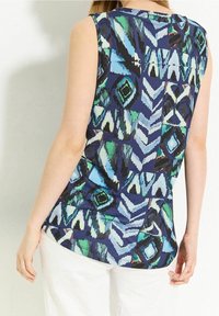 Ärmlös topp med ett blått och grönt abstrakt geometriskt mönster, med rund halsringning och avslappnad passform. Slät tygstruktur.