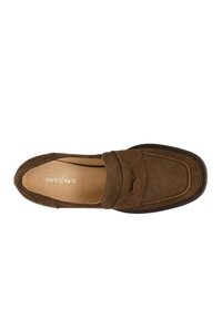 Mocassin en suède marron à enfiler avec des coutures détaillées et une semelle texturée. Présente un design découpé subtil sur le devant.