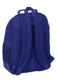 Niebieski plecak z materiału z wyściełanymi szelkami, teksturowaną siateczkową kieszenią boczną i wyraźnymi detalami przeszyć. Posiada mocny uchwyt u góry.