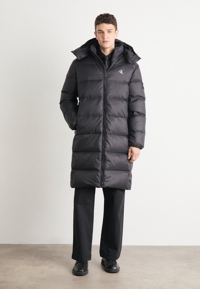 Schwarze Daunenjacke mit gestepptem Design, hohem Kragen, durchgehendem Reißverschluss und Seitentaschen. Leichtes, isoliertes Material bietet Wärme.