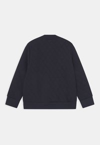 Mörkblå vadderad jacka med lång ärm, ribbad mudd och nederkant, visad bakifrån mot en vit bakgrund.