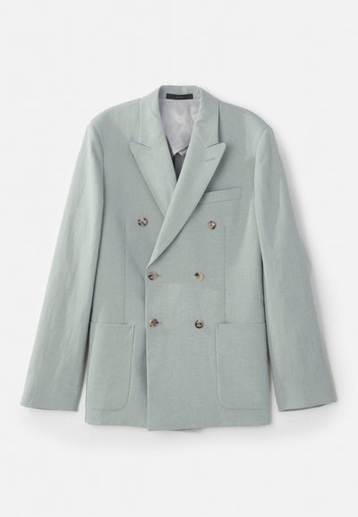 Kaksikardiga jakki helesinisest kangast, millel on sälgudega krae, kaks esistaskut ja pruunid nupud. Sile tekstuur.