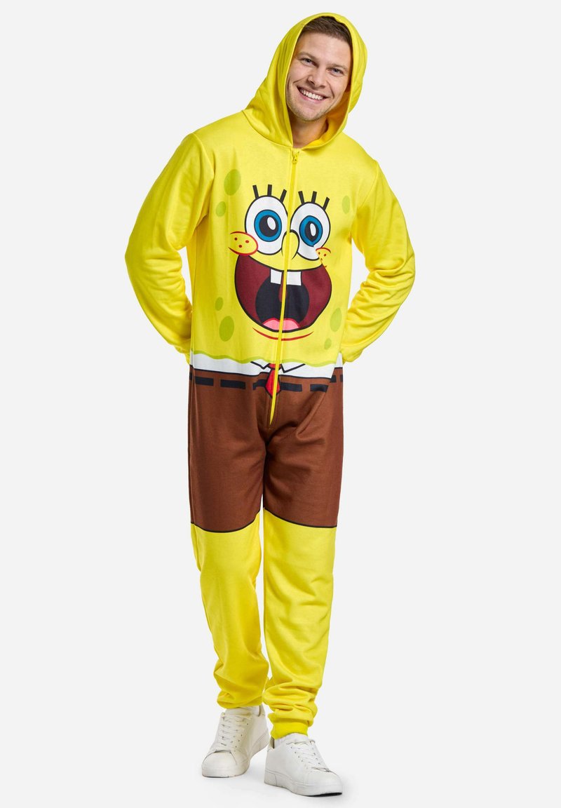 Geltona su kapuci vienodera su dideliu SpongeBob SquarePants piešiniu, rudos spalvos kelnių dalimi ir užtrauktuko uždarymu. Slydus, minkštas audinys.