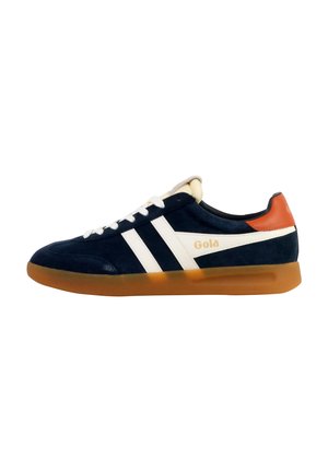 Granatowe zamszowe sneakersy z białymi pasami, pomarańczowym akcentem na pięcie i gumową podeszwą. Wyposażone w białe sznurowadła oraz logo "Gola" po boku.