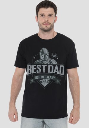 Schwarzes Baumwoll-T-Shirt mit einem Grafikdesign, das den Text "BESSTER PAPA NR. 1 IM GALAXIE" und Figuren zeigt. Mit kurzen Ärmeln und Rundhalsausschnitt.