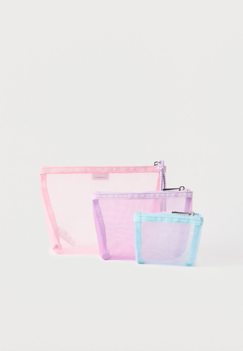 Τρεις κενές, διαφανείς θήκες με φερμουάρ από δίχτυ, σε ροζ, μωβ και ανοιχτό μπλε, τοποθετημένες κατά μέγεθος πάνω σε λευκό φόντο.