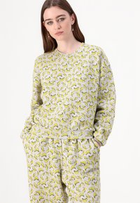 Conjunto de sweatshirt e calças cinza com um padrão repetido de bananas. Feito de material suave com um corte descontraído e punhos canelados.