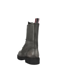 Bottine de combat mi-mollet en cuir gris foncé avec une épaisse semelle en caoutchouc noir, une languette à l'arrière avec des rayures rouges, blanches et noires, et un logo en relief près du talon.