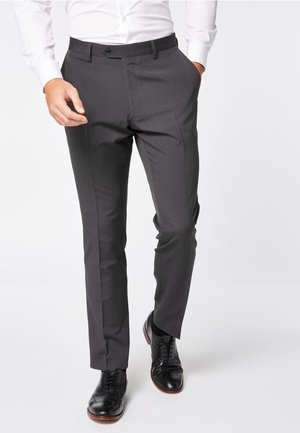 Pantalones grises ajustados con una textura suave, que cuentan con un cierre de botón y bolsillos laterales, combinados con zapatos negros pulidos.