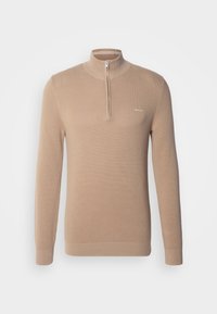 Maglione a maniche lunghe beige in maglia con colletto a mezza zip e piccolo logo bianco sul lato sinistro del petto su uno sfondo semplice.