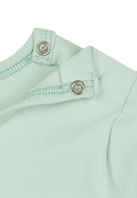 Tessuto in cotone verde menta chiaro presenta un colletto a coste e bottoni a pressione. La trama è liscia con una leggera elasticità.