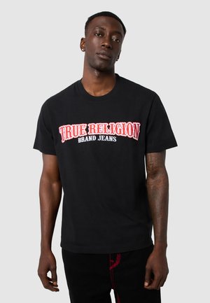 Black cotton t-shirt featuring bold red and white "TRUE RELIGION BRAND JEANS" graphic text on the front. Short sleeves, round neckline.