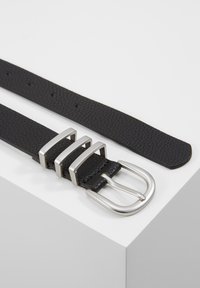 Cinto de couro preto com acabamento texturizado. Apresenta uma fivela de metal prateado com três realces horizontais. Ajustável com vários furos.