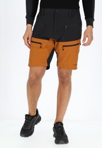 Heren shorts met een zwarte bovenkant en een oranje onderkant. Voorzien van meerdere ritszakken en een duurzame, gestructureerde stof. Zwarte accenten aan de zijkanten.
