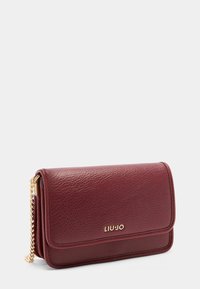 Bordeaux læder clutch med en tekstureret finish, guld kædestrop og præget logo. Har en flaplukning og en slank rektangulær form.