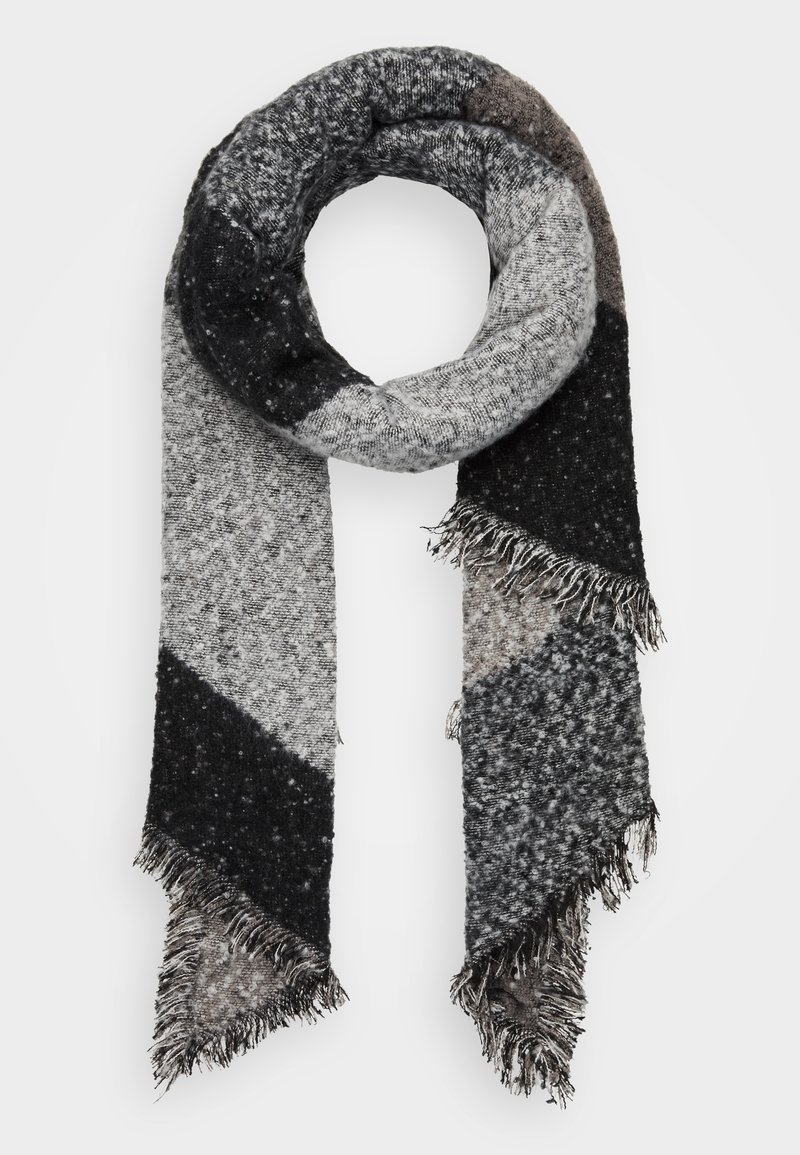 Écharpe tricotée noire, grise et blanche avec des blocs de couleur diagonaux et des extrémités à franges, enroulée en forme circulaire sur fond blanc.