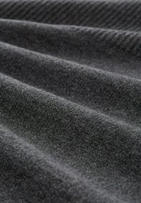 Tessuto grigio scuro con una texture morbida, caratterizzato da sottili motivi a coste e una finitura liscia, disposti in morbidi pieghe.