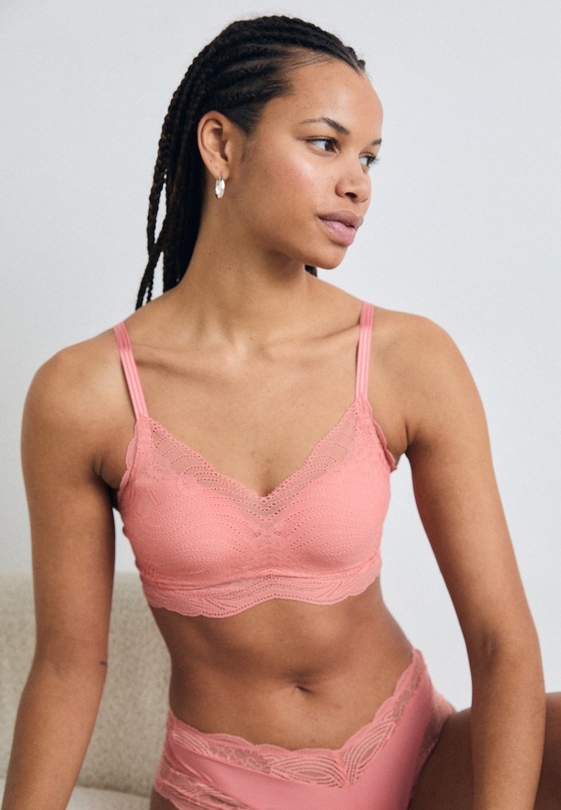 Rosa blonde bralette med bølgende kantdesign. Har tynne justerbare stropper og teksturerte detaljer. Matchet med undertøy i samme blonde.