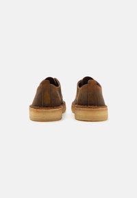 Brown leather shoes with rounded toes, stitched detailing, and a light-colored rubber sole. No visible patterns or hardware.