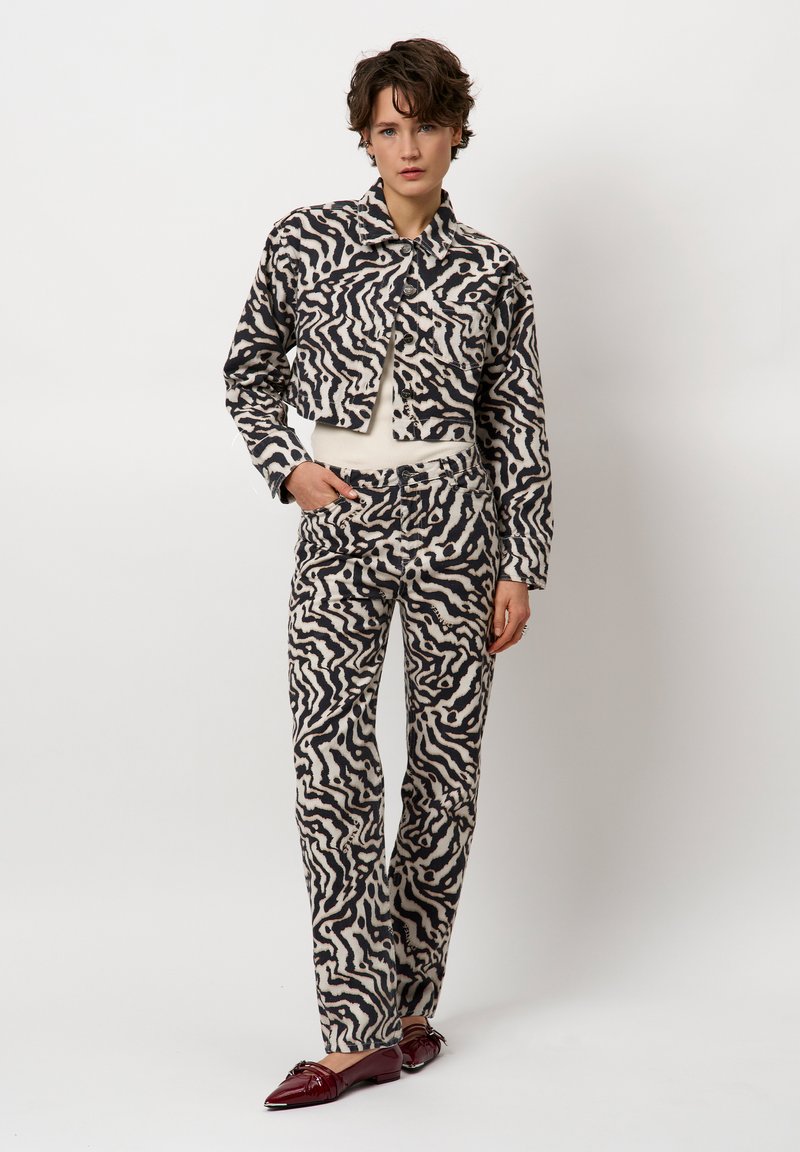 Geknipte jas en bijpassende broek in een crèmekleurig en zwart abstract golfpatroon, met knoopdetails en een strakke pasvorm. Echte leren schoenen.