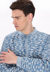 Blue jacket with a repetitive fish pattern, zip front closure, and soft texture. Light blue collar and cuffs complement the design.