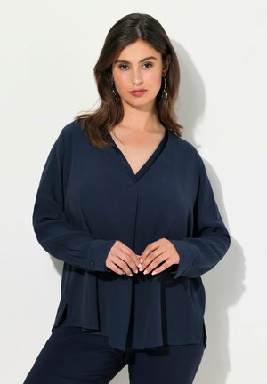 Blouse bleu marine à manches longues avec un col en V et des poignets à boutons ; coupe décontractée avec un design drapé et des fentes sur les côtés pour plus de facilité de mouvement.