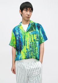 Lühikeste varrukatega särk, millel on erksates sinistes ja rohelistes toonides abstraktne muster, valmistatud kergest materjalist, vasakul rinnal taskuga.