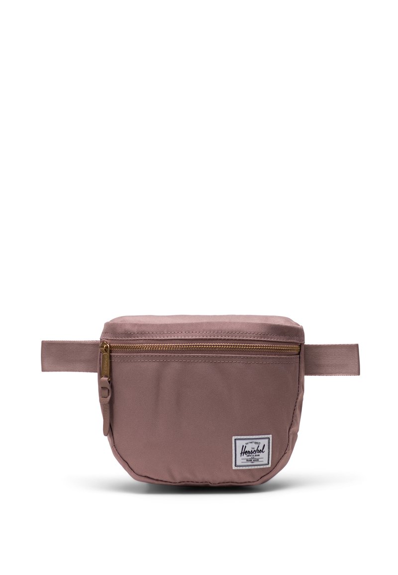 Marsupio Herschel in rosa tenue con zip dorata, realizzato in tessuto, forma rettangolare piatta e patch con logo distintivo sul davanti.