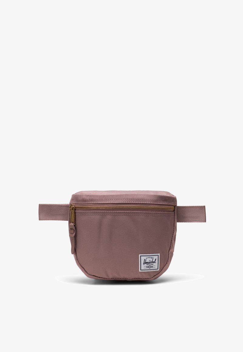 Marsupio Herschel in rosa tenue con zip dorata, realizzato in tessuto, forma rettangolare piatta e patch con logo distintivo sul davanti.