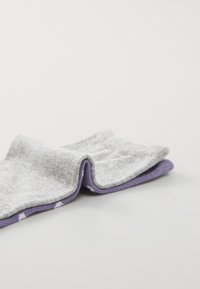 Due calzini piegati, uno grigio con una texture morbida e l'altro viola al polsino, poggiati su una superficie bianca pulita.
