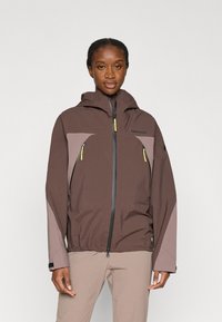 Καφέ αδιάβροχο μπουφάν με γκρι λεπτομέρειες, ρυθμιζόμενο καπό, τσέπες με φερμουάρ και ελαστικά μανίκια. Ελαφρύ, σχεδιασμένο για υπαίθρια δραστηριότητα.