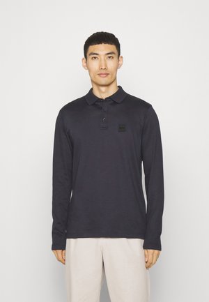Navyblauwe polo met lange mouwen, voorzien van een klassieke kraag, drie knopen en een klein zwart logo aan de borst. Van een katoenmix.