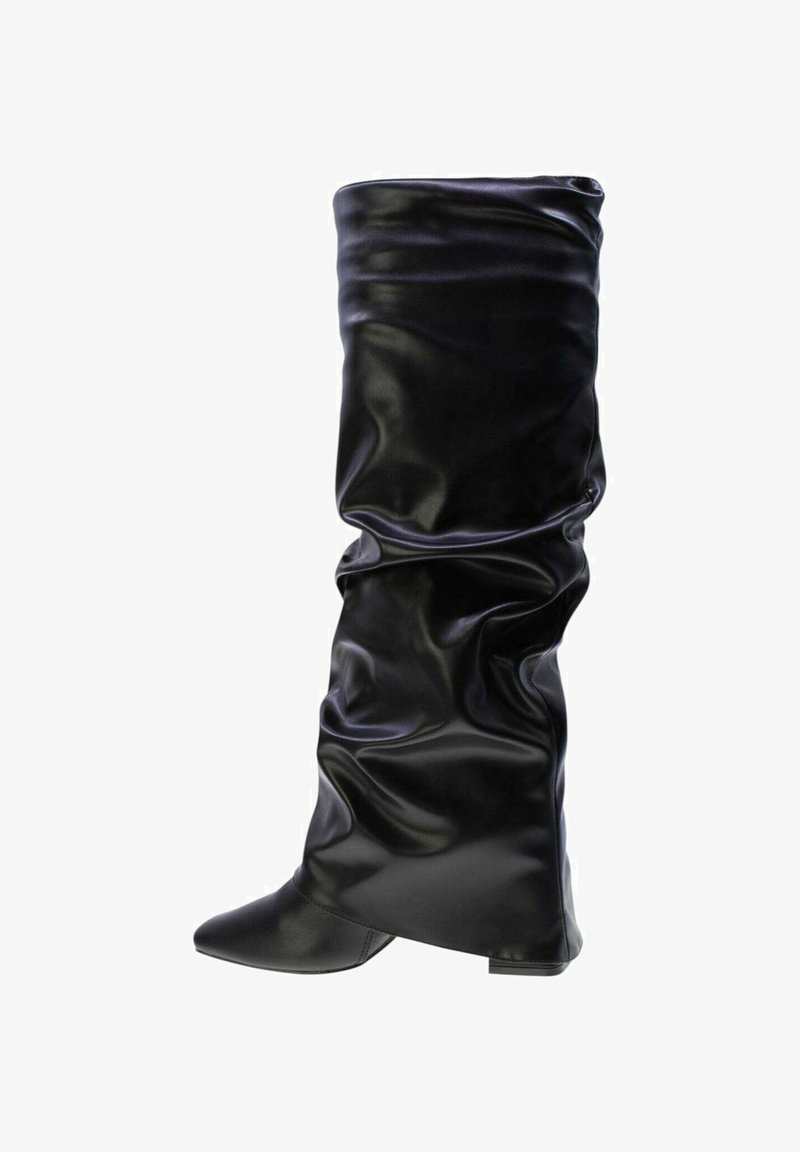 Stivale in pelle nero slouchy, alto fino al ginocchio, con punta affilata e tacco basso, isolato su sfondo bianco.