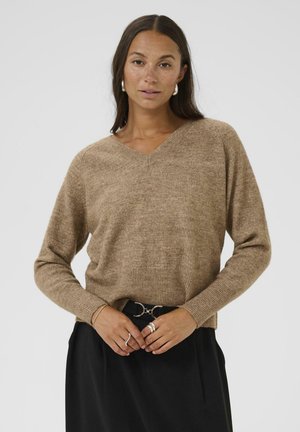 Bruine, gestructureerde v-hals trui met lange mouwen en geribbelde zoom, gedragen over zwarte highwaisted broek met een riem met ronde hardware.