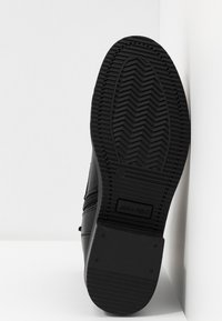 Černá podrážka boty s texturovaným, cik-cak vzorem a výrazným vzorkem. Viditelný boční zip a značení na podrážce. Velikost 37.