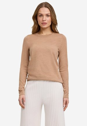 Beige long-sleeve sweater with a round neckline, made of soft fabric; features a relaxed fit and simple design. Paired with pleated white pants.