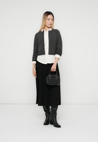 Gray wool cardigan, white button-up shirt, black pleated skirt, and knee-high black leather boots. Small black textured handbag with metal hardware.