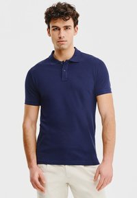 Granatowa koszulka polo z bawełny, z klasycznym kołnierzykiem, zapięciem na dwa guziki i krótkimi rękawami, z subtelnym logo na klatce piersiowej.