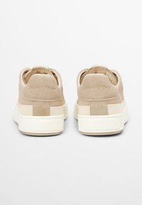 Beige suede sneakers with a textured design and cream rubber soles. Features a back pull tab and embossed logo on the heel.