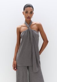Gray halter-top made from textured fabric, featuring a twisted tie at the neck and loose, flowing design. Paired with matching wide-leg pants.