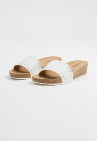 Sandalias deslizantes blancas con una correa texturizada que presenta acentos de strass. Suela de corcho con cuña y fondo de goma blanca con relieve.