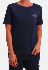 Granatowy t-shirt z krótkim rękawem i okrągłym dekoltem, z małym haftowanym logo na piersi. Miękka, gładka tkanina.